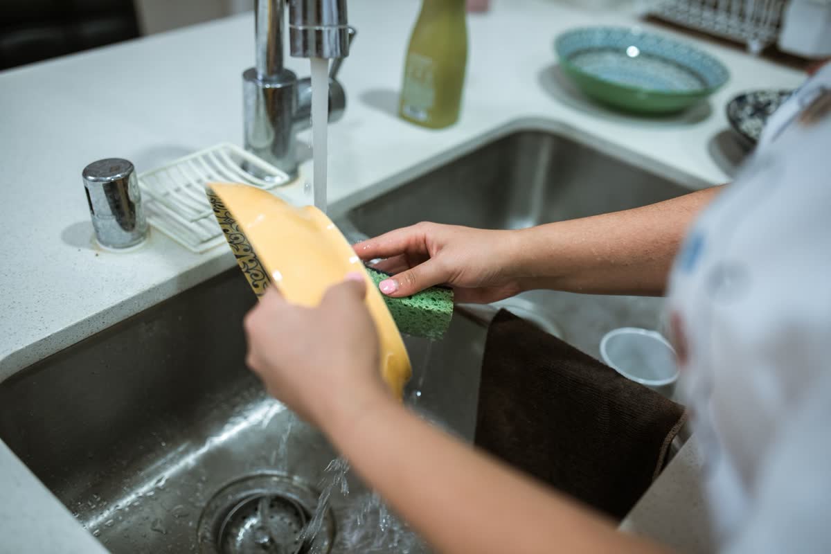 Washing a dish with a sponge at a sink