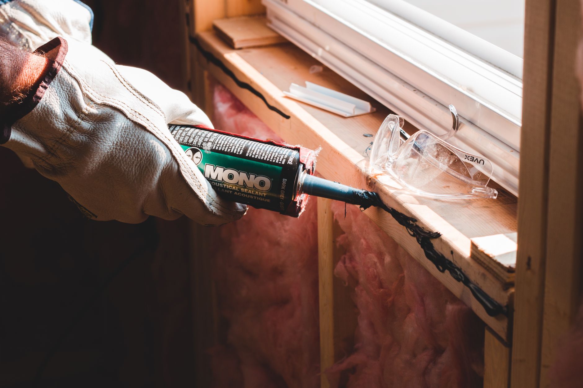 A caulking gun sealing a gap around window trim