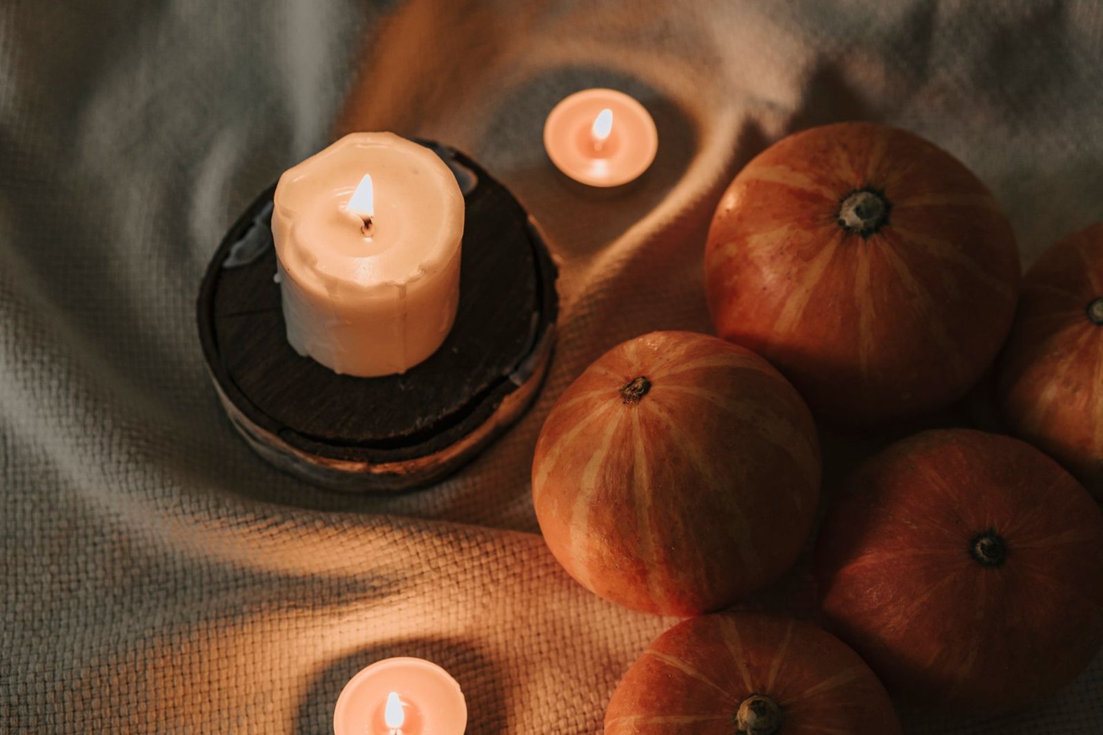 Cozy indoor pumpkins and candles on soft fabric